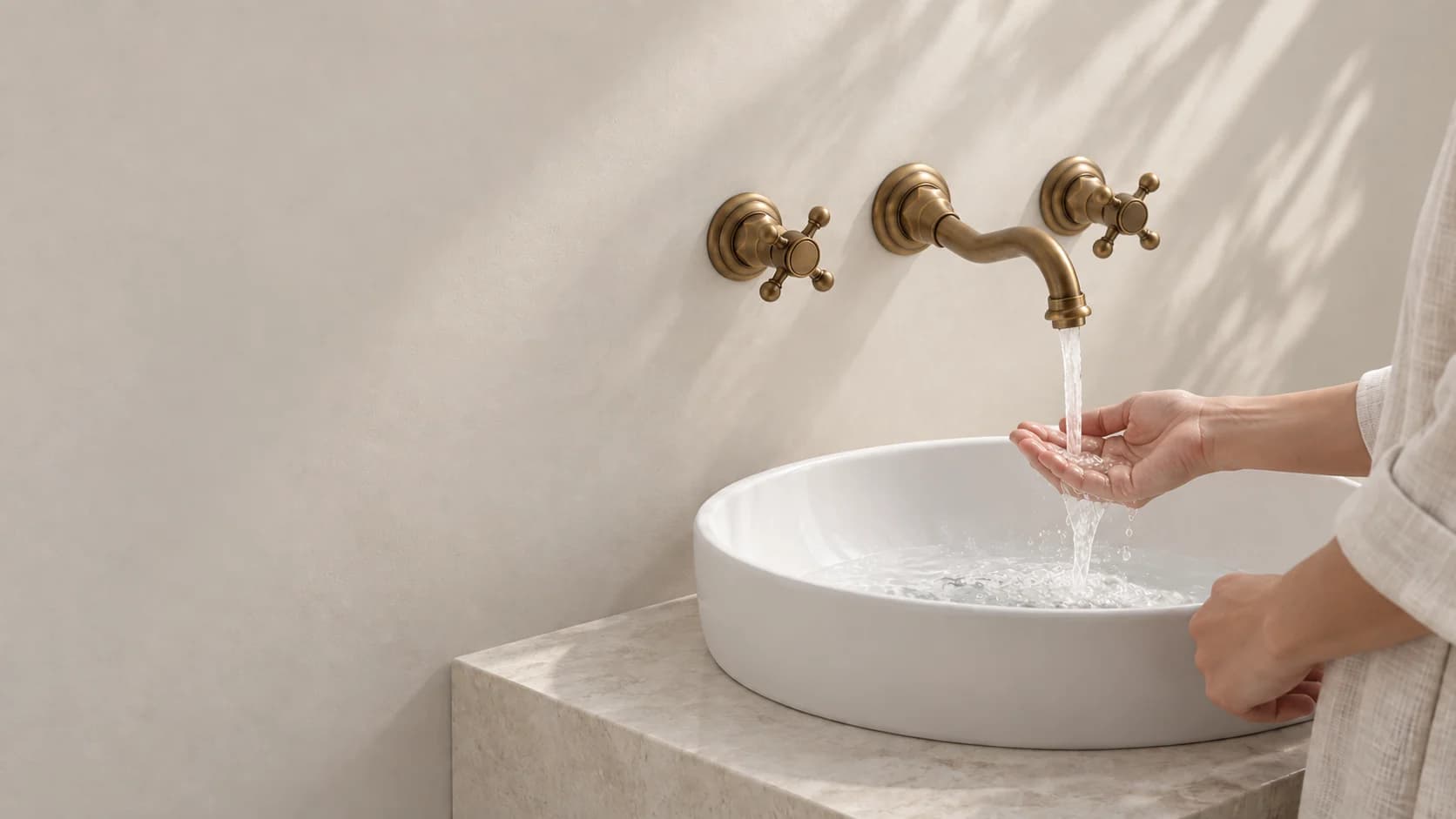 Rubinetto da bagno a parete EYN AQ0732 in ottone anticato sopra il lavabo, con una persona adulta sulla destra che verifica il flusso dell’acqua.